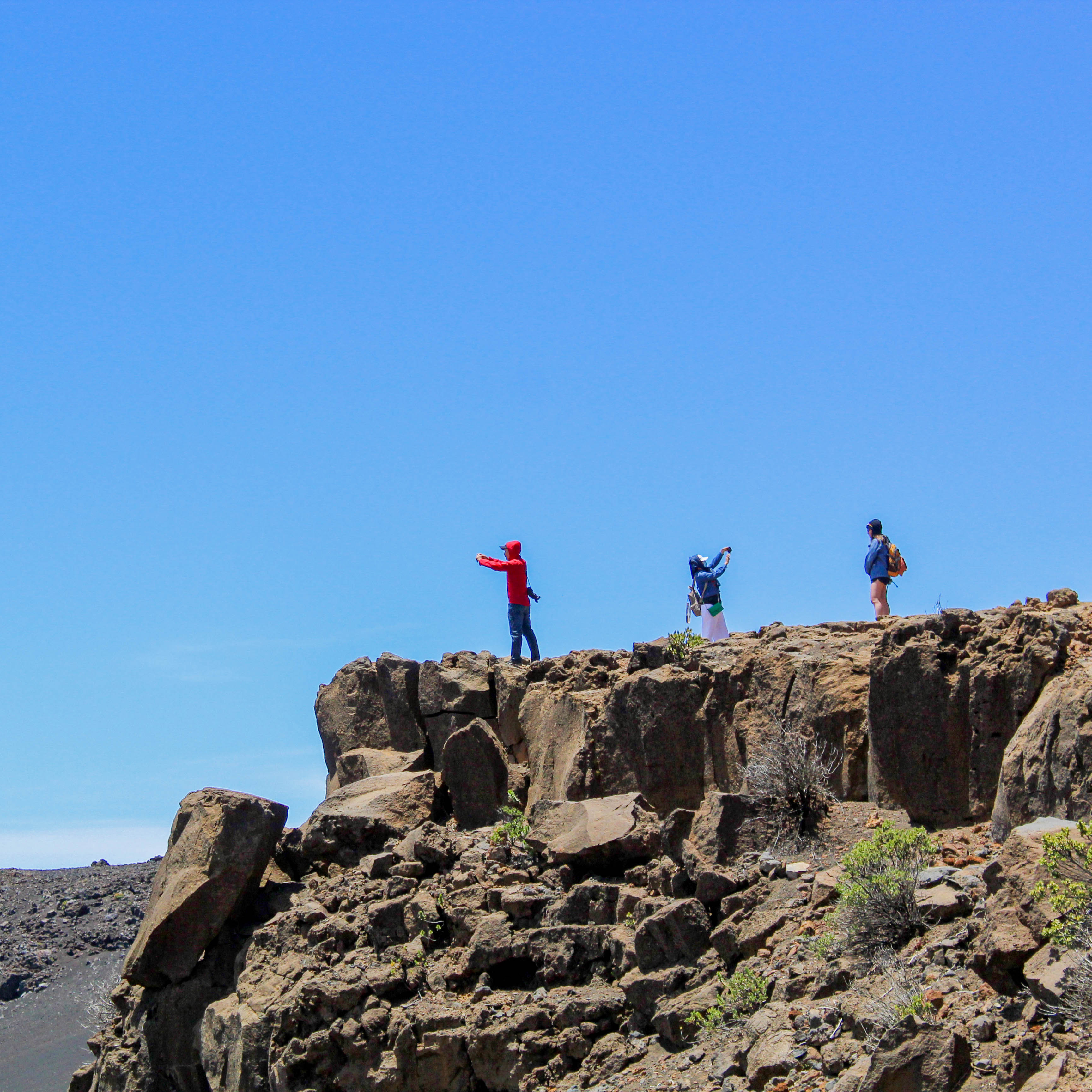 Image of three people on a cliff.