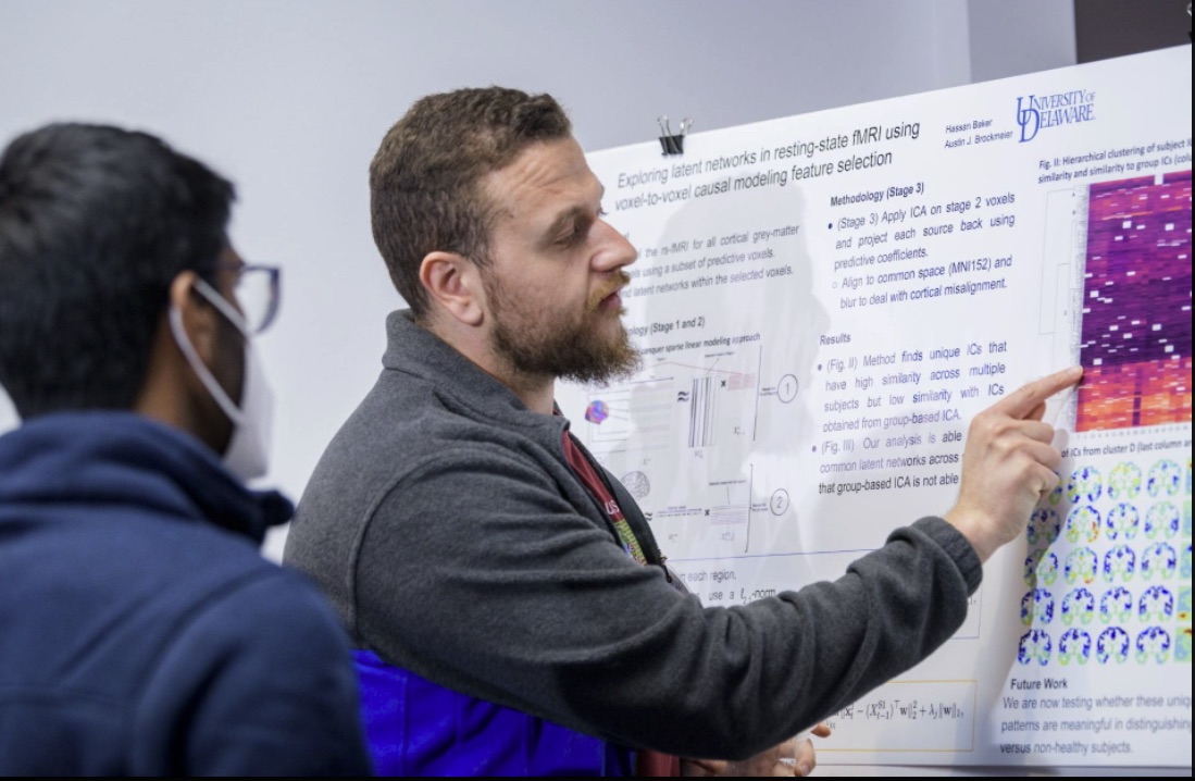 Hassan presents his poster to another attendee of the 2022 DARWIN